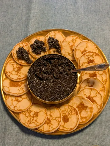 Canapé catering Manila — golden platter of blini topped with caviar around a central caviar bowl